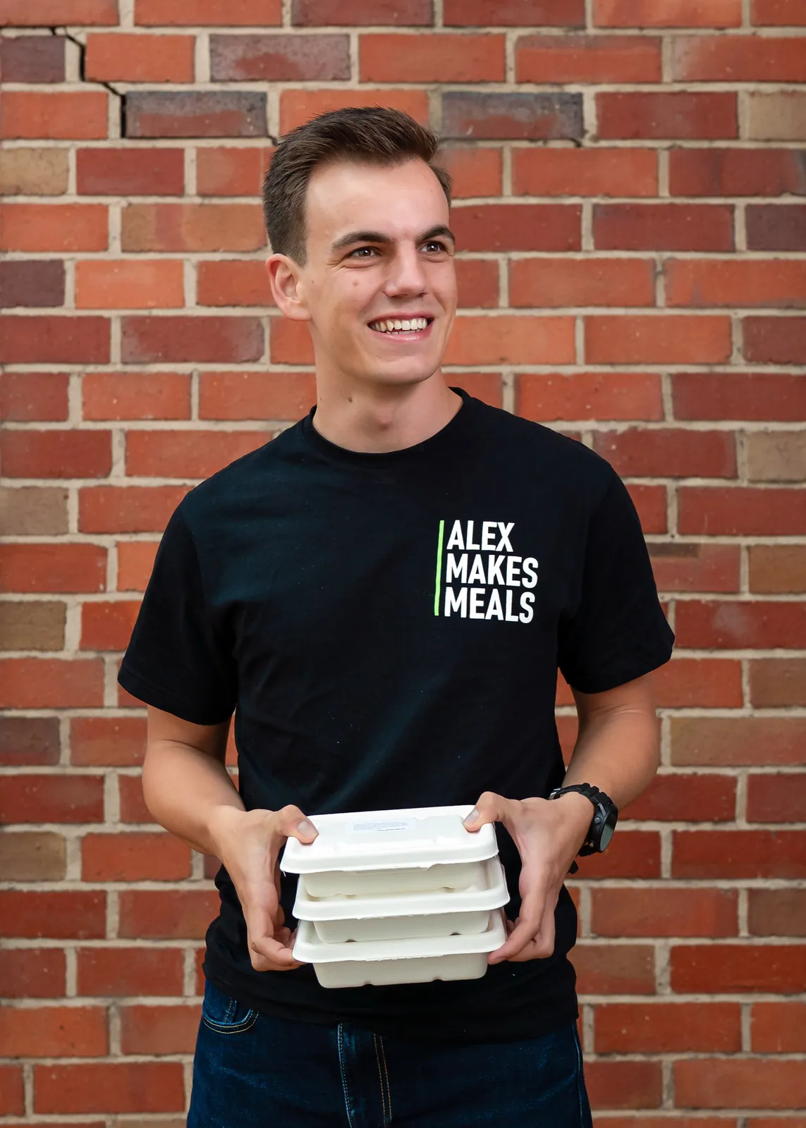 Alex holding Alex Makes Meals containers outside the kitchen