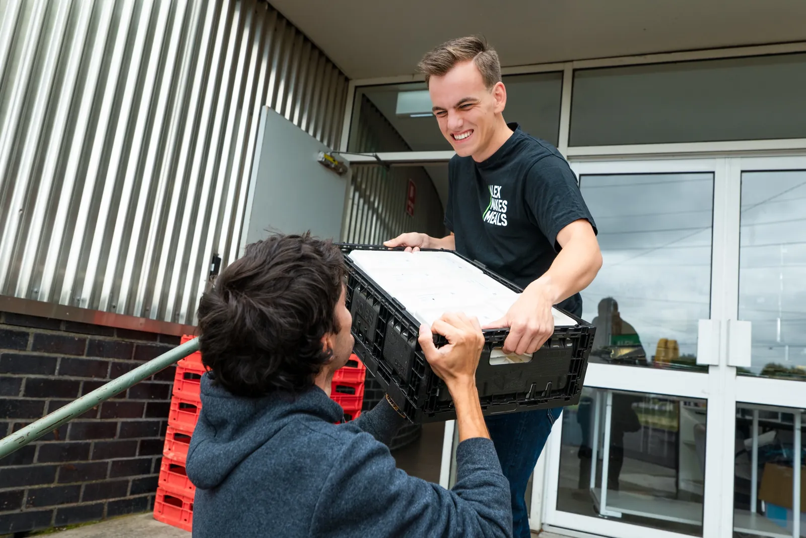 Alex loading a crate of meals for delivery