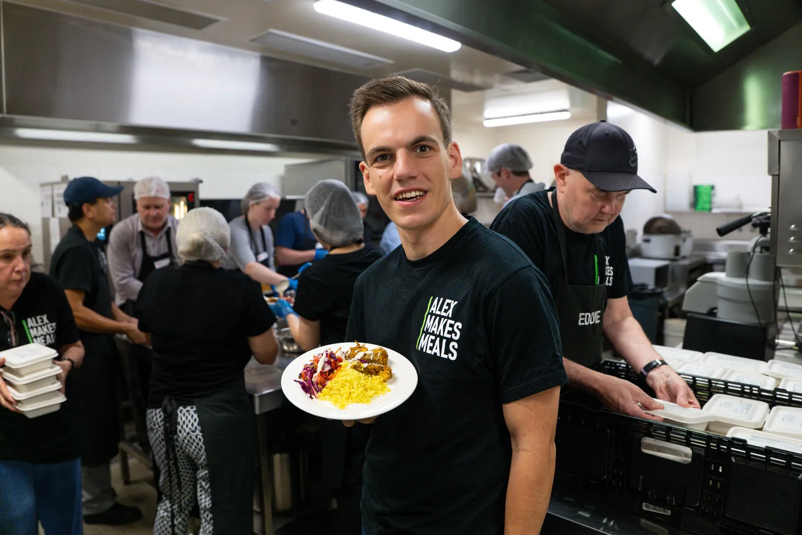 Alex holding a plated meal in the Alex Makes Meals kitchen
