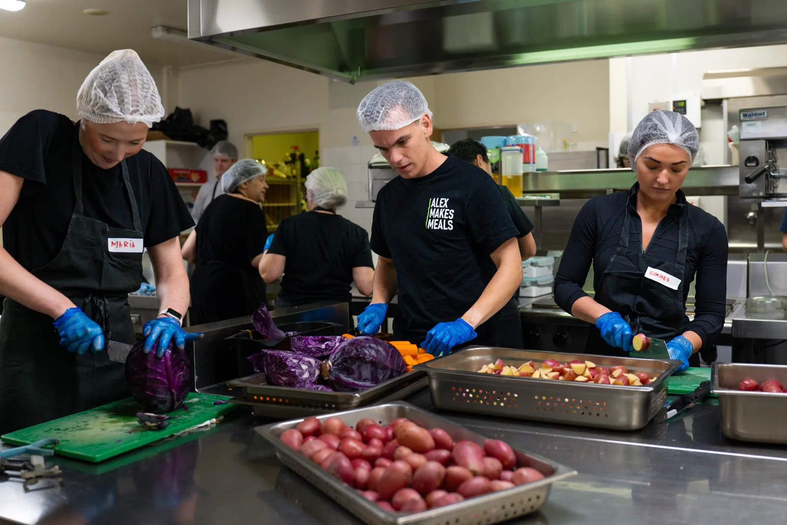 Volunteers preparing vegetables in the Alex Makes Meals kitchen